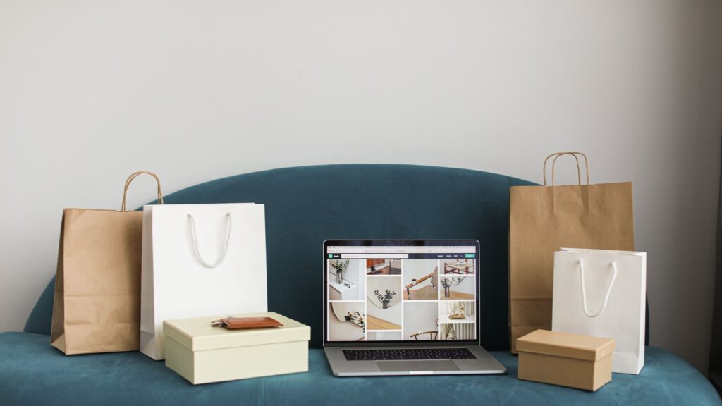 Portátil con una tienda online abierta junto a bolsas y cajas de pedidos